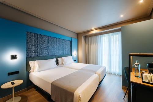 a bedroom with a large bed with a blue wall at Abba Rambla Hotel in Barcelona