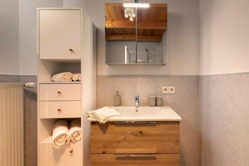 a bathroom with a sink and a cabinet and towels at Ferienwohnen beim Hirsch in Hopferau