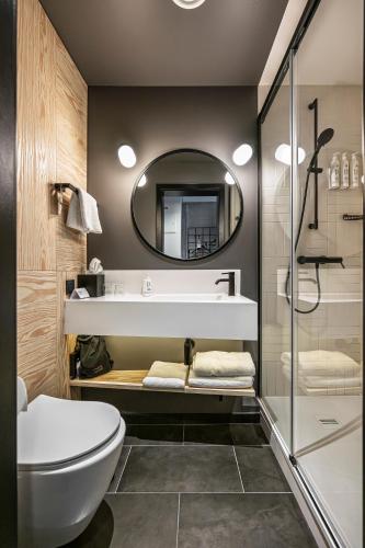 a bathroom with a sink and a toilet and a mirror at Moxy Kaunas Center in Kaunas