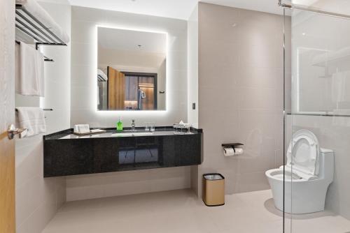 a bathroom with a sink and a toilet and a mirror at The Everly Lhesson Kuching in Kuching