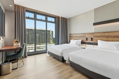 a hotel room with two beds and a desk at The Everly Lhesson Kuching in Kuching