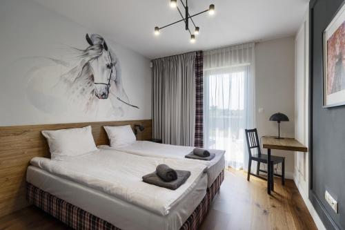 a bedroom with a bed with a horse painting on the wall at Osada Hipodrom in Łąck