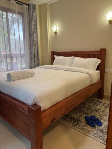 a bed in a bedroom with a window andippers on the floor at Raha Home within Nakuru CBD with pool and gym in Nakuru