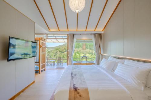 a bedroom with a bed and a flat screen tv at Chang'E Villa Rakthai in Ban Rak Thai