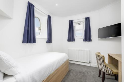 a bedroom with a bed and a desk and a tv at The Sandringham Hotel in Weston-super-Mare