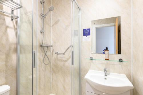 a bathroom with a shower and a sink and a mirror at The Sandringham Hotel in Weston-super-Mare
