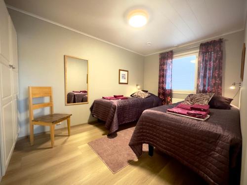 a bedroom with two beds and a mirror and a chair at Riihen Tupa in Äkäslompolo