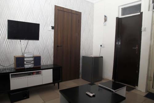 a living room with a television and a wooden door at Sunshine Place C1 in Lagos