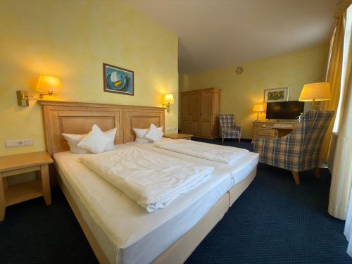 a bedroom with a large white bed and a desk at Strandhotel Sonnenburg by ANS in Kühlungsborn