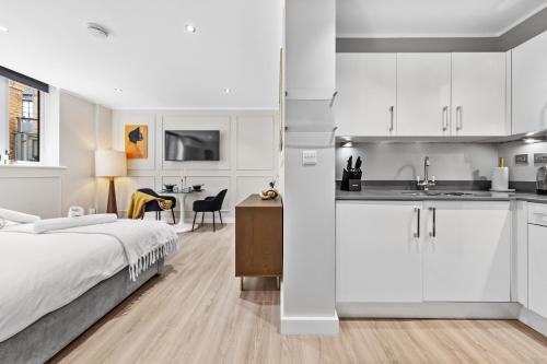 a white bedroom with a bed and a kitchen at The Liverpool Street Boutique in London