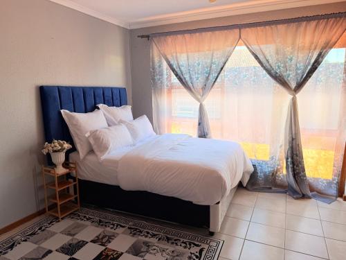 a bedroom with a bed and a large window at Zahies Accommodation in Panorama