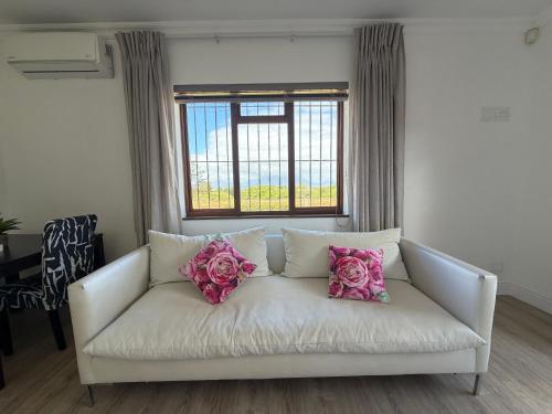 a white couch with pink pillows in a living room at Plattekloof Mountain view in Plattekloof