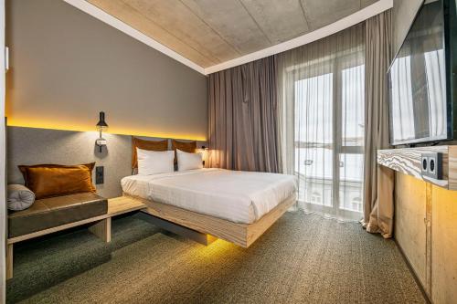 a hotel room with a bed and a window at Moxy Kaunas Center in Kaunas