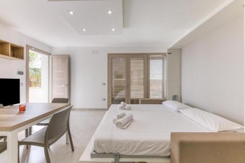 a white bedroom with a bed and a table and a desk at La Spiaggetta 2 in Torre San Giovanni Ugento