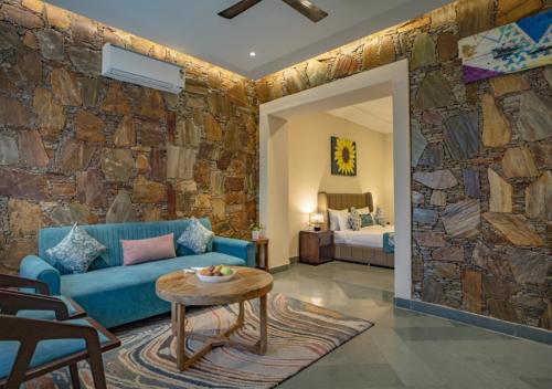 a living room with a blue couch and a stone wall at Maanya by the Lake By Samav hotels in Udaipur