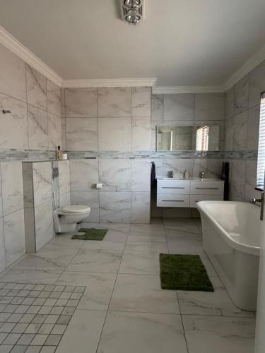 a white bathroom with a tub and a toilet and a sink at Plattekloof Mountain view in Plattekloof