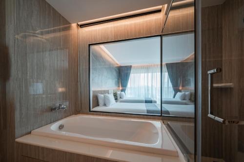 a bathroom with a tub and a large mirror at Mandarin Eastville, Pattaya - SHA Extra Plus in North Pattaya