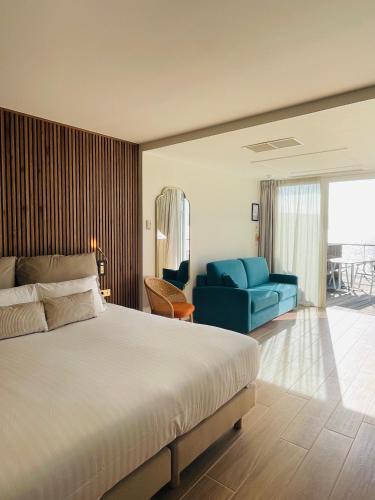 a bedroom with a bed and a blue couch at Les Sables Blancs in Concarneau
