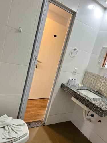 a bathroom with a toilet and a sink and a mirror at Hotel Econômico in Volta Redonda