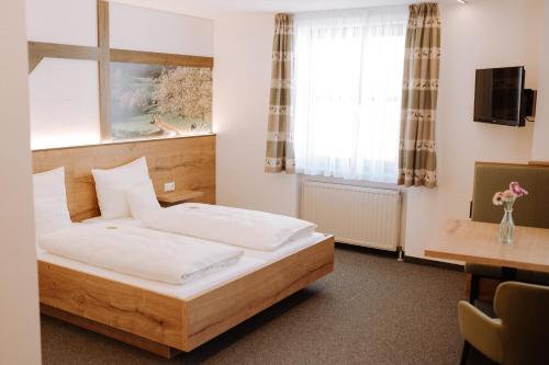 a bedroom with a bed and a desk and a window at Hotel zur Post e.K. in Waischenfeld