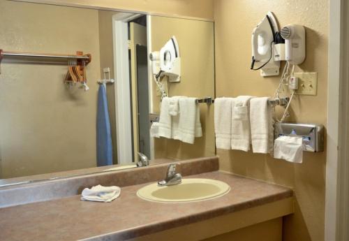 ein Badezimmer mit einem Waschbecken, einem Spiegel und Handtüchern in der Unterkunft Americas Best Value Inn Crosstimbers in Stephenville