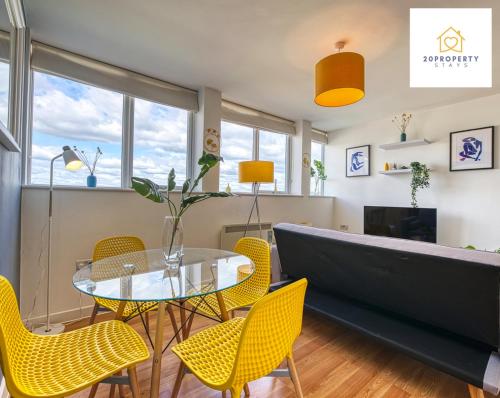 a dining room with a glass table and yellow chairs at Contractors and Relocations Haven with Parking in Basingstoke