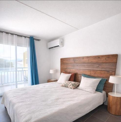 a bedroom with a large bed with a wooden headboard at Studio LY'S in Saint-François