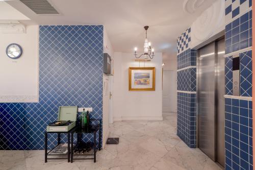 a hallway with blue tile walls and a clock at Magnolia Tbilisi in Tbilisi City