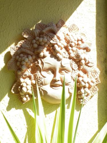 a statue of a face with grapes on a wall at Villa Sant’Uberto Country Inn in Radda in Chianti