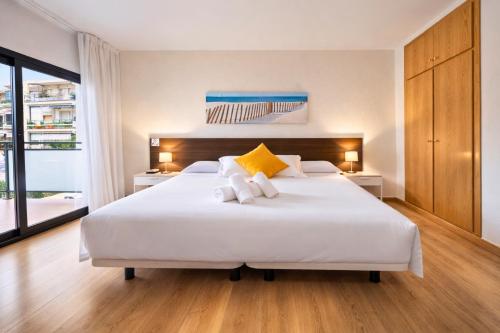 ein Schlafzimmer mit einem großen weißen Bett und gelben Kissen in der Unterkunft Adia Hotel Cunit Playa in Cunit