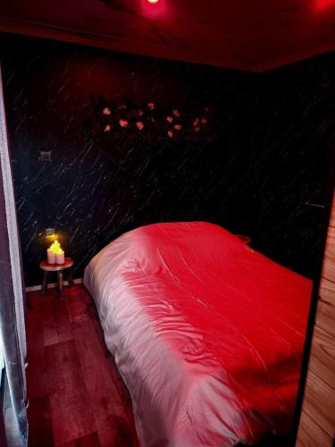 a red bed in a room with a table with a candle at Le Nid Douillet du Tacot in Le Thillot