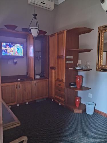 a living room with a tv and wooden cabinets at Bohemian Guesthouse - Pretoria in Pretoria