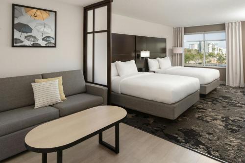 a hotel room with two beds and a couch at City Express by Marriott Orlando International Drive in Orlando