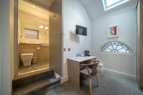 a bathroom with a toilet and a table with a chair at Number One Townhouse in Kinsale