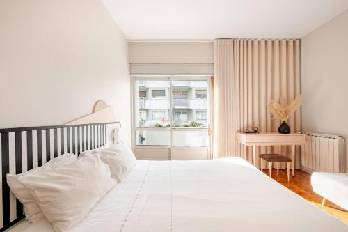 a bedroom with a white bed and a window at AMAZING DUPLEX - Mid Century Experience & PARKING in Porto