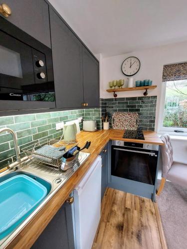 a kitchen with a sink and a clock on the wall at The Pack Horse Exmoor National Park Allerford Riverside Cottage & Apartments in Minehead