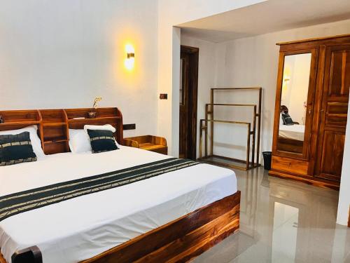 a bedroom with a large bed and a mirror at Coral Bay Villa in Pottuvil