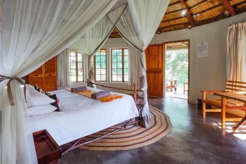 a bedroom with a canopy bed and a table at Mlilwane Game Sanctuary in Lobamba