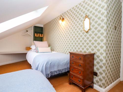 a attic bedroom with two beds and a dresser at Old Sunday School in Bideford