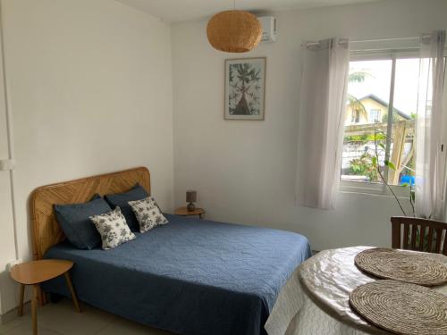 a bedroom with a blue bed and a window at O kAZ de Petite île in Petite Île