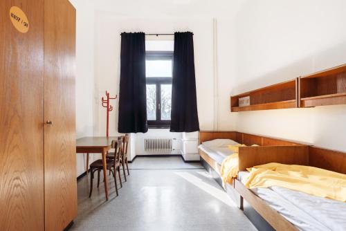 a bedroom with two beds and a table and chairs at NUMBR25 - self service & low budget Hotel in Graz