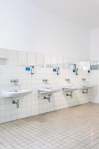 a public bathroom with three sinks and mirrors at NUMBR25 - self service & low budget Hotel in Graz