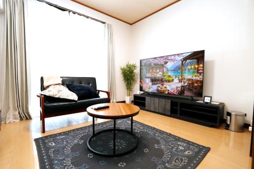 a living room with a couch and a tv at Free Rental Car Villa in Beppu
