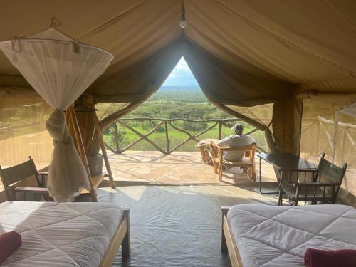 a man sitting in a tent with a view at Maasai Wild Adventure in Gatunga