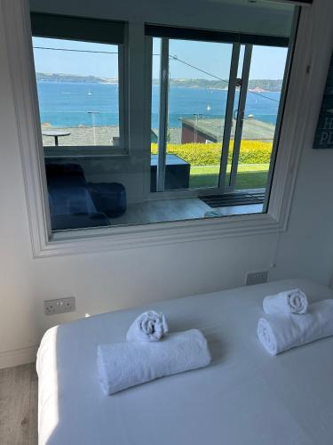 a bedroom with a large window with towels on a bed at Bovisand Beach Area Chalet, 2-Bed Sea View with Gated Parking & BBQ in Plymouth
