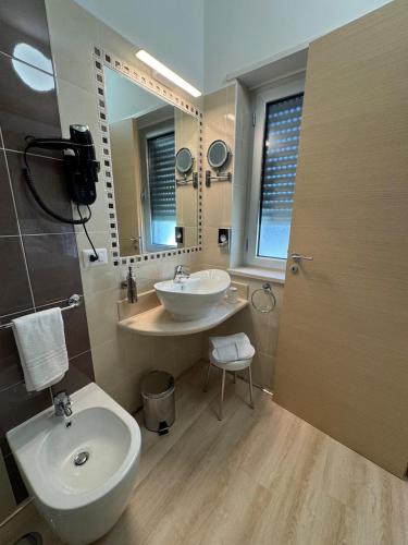 a bathroom with a sink and a toilet and a mirror at Hotel Floris in Rende