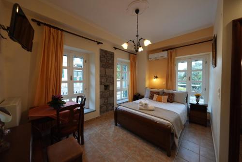 a bedroom with a bed and a table and windows at Artemis Traditional Hotel in Myrina