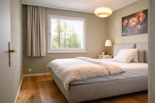 a bedroom with a large bed and a window at Chalet Höfi - Ski-in Ski out at Hörnlilift by Arosa Stay in Arosa