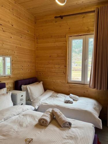 two beds in a log cabin with two windows at Koçeku Brothers Guest House in Fushë-Lurë