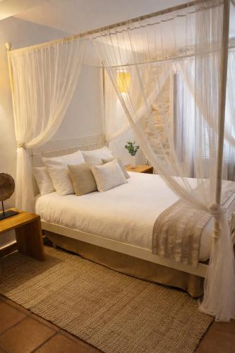 a bedroom with a canopy bed with white curtains at La Posada De Lola in El Molar